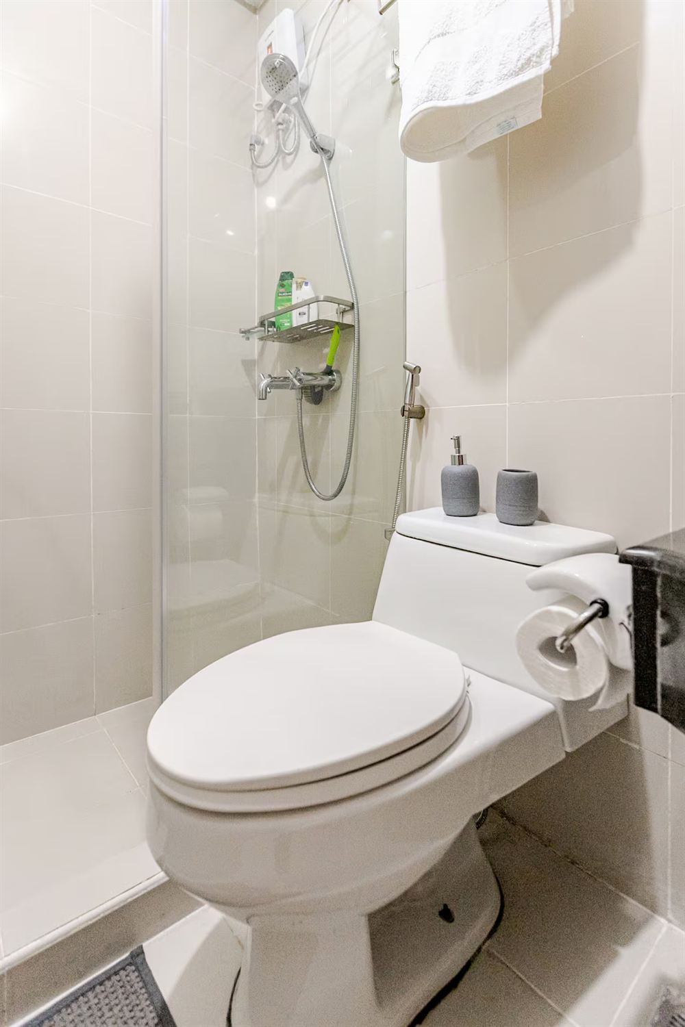 The bathroom with a glass shower screen, white tiling and folded towels