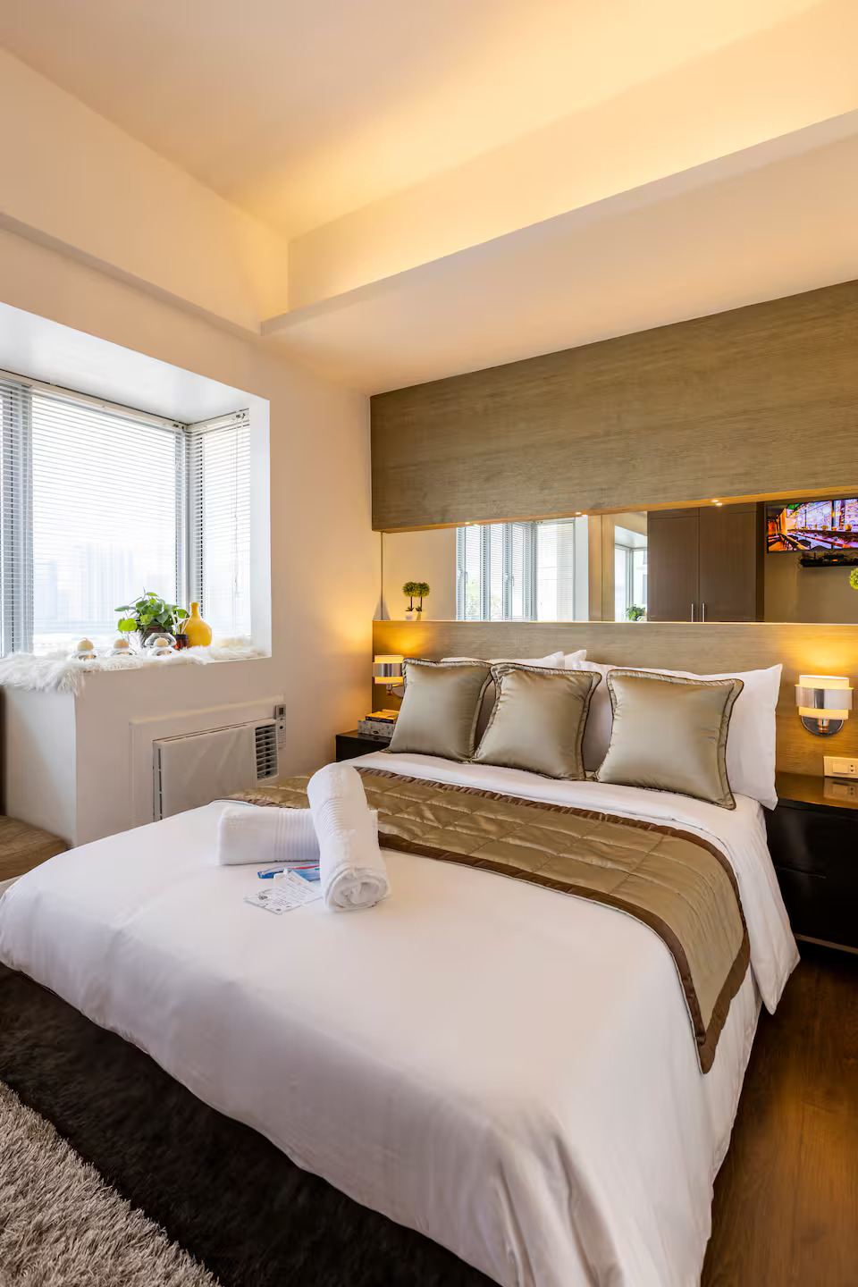 The bed made up in white linen beside a bright corner window